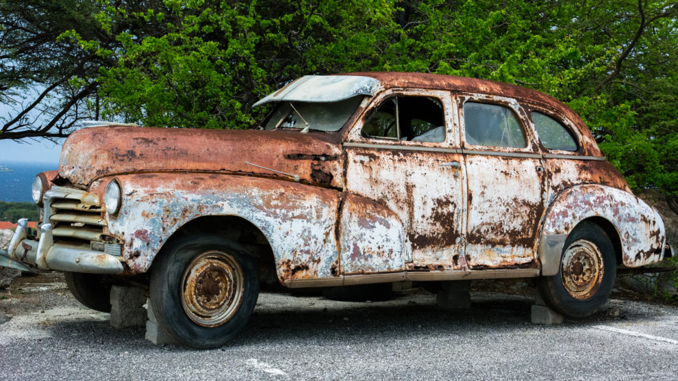 a rusty, falling apart vintage car